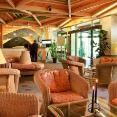 Lobby d'hôtel avec fauteuils en rotin, lampes et réception.