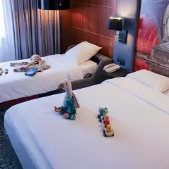 Chambre d'hôtel avec deux lits, jouets et vêtements pour enfants.