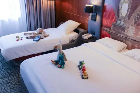 Chambre d'hôtel avec deux lits, jouets et vêtements pour enfants.