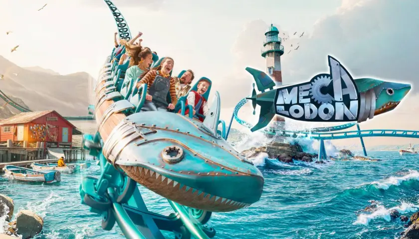 Un train de montagnes russes en forme de requin mécanique sur l'eau, avec un phare et un village de pêcheurs.