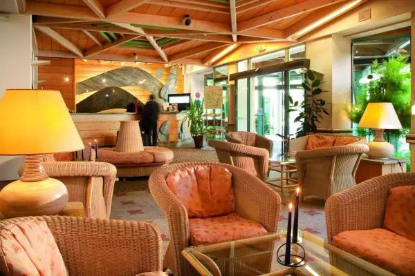 Lobby d'hôtel avec fauteuils en rotin, lampes et réception.